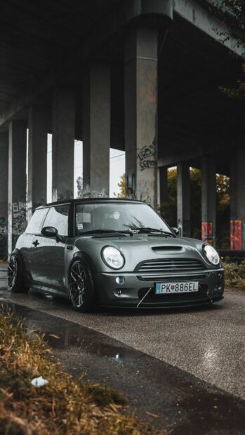 A sleek Mini Cooper is parked on a wet road under a concrete bridge, Mini Cooper Wallpapers 4K, HD Mobile Wallpaper