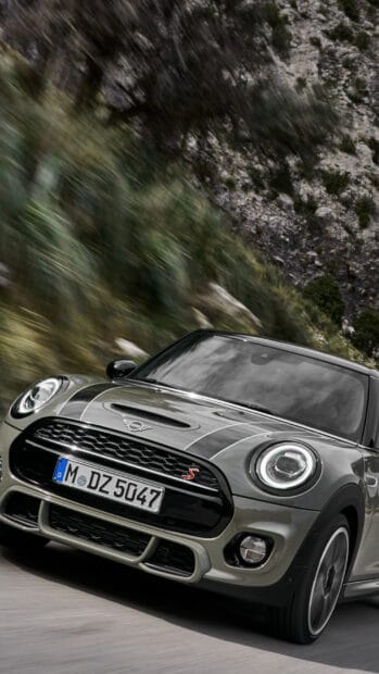 A Mini Cooper is speeding along a winding mountain road surrounded by greenery, HD Mobile Wallpaper