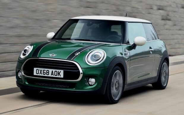 A green Mini Cooper with white roof is driving on a road next to a stone wall, HD Desktop Wallpaper