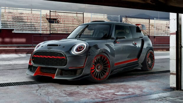 A sleek Mini Cooper with red detailing is parked in a racing garage, 2K Desktop Wallpaper