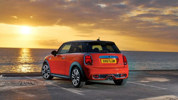 A red Mini Cooper is parked near the sea at sunset showing the rear view with glowing sky, HD Desktop Wallpaper