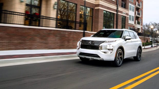 A white Mitsubishi Outlander driving on a city street with brick buildings in the background, HD Desktop Wallpaper