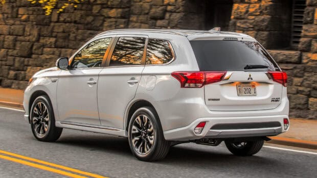A white Mitsubishi Outlander drives past a stone wall on an urban street in this image, HD Desktop Wallpaper
