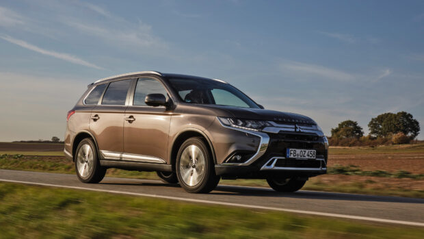 A Mitsubishi Outlander driving along a rural road with fields and trees in the background, 4K Desktop Wallpaper