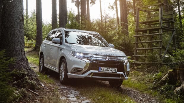 A white Mitsubishi Outlander driving on a rocky forest trail surrounded by trees, 4K Desktop Wallpaper