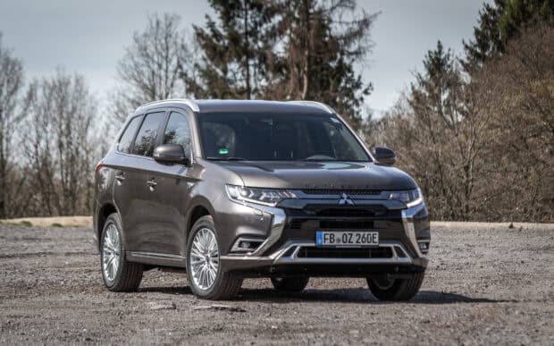 A brown Mitsubishi Outlander parked on gravel near forest under cloudy sky, HD Desktop Wallpaper