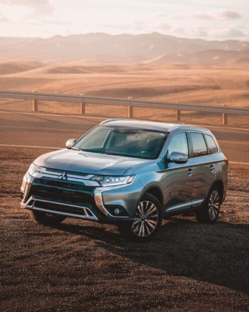 A Mitsubishi Outlander is parked on a desert road with mountains in the background, HD Phone Wallpaper