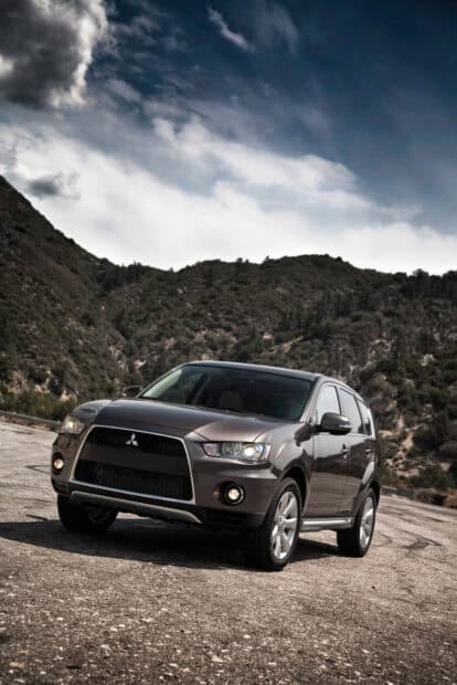 A Mitsubishi Outlander is parked on a rocky ground with mountains and a cloudy sky in the background, HD Mobile Wallpaper