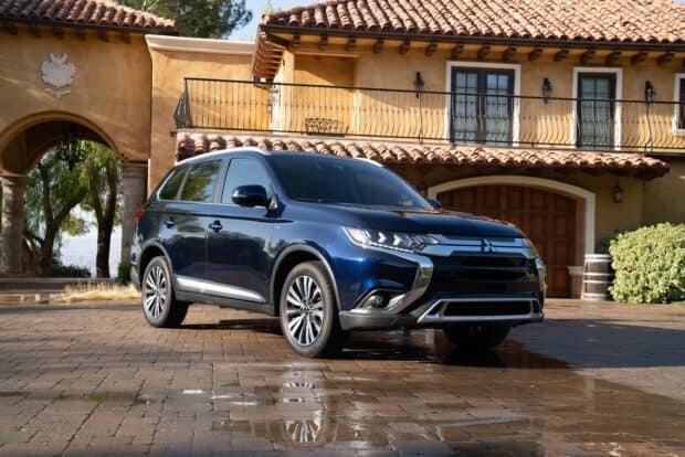 A blue Mitsubishi Outlander parked on the driveway of a Mediterranean style house with tile roof, 2K Desktop Wallpaper