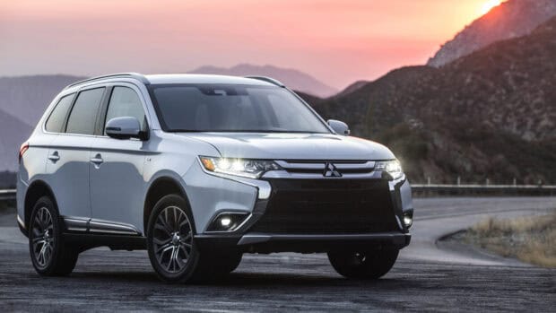 A silver Mitsubishi Outlander drives on a curved mountain road at sunset, 4K Desktop Wallpaper