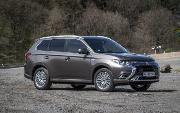 A gray Mitsubishi Outlander is parked on a gravel surface with a forest background, HD Desktop Wallpaper