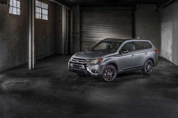 A silver Mitsubishi Outlander is parked inside a dimly lit urban garage with concrete walls, HD Desktop Wallpaper