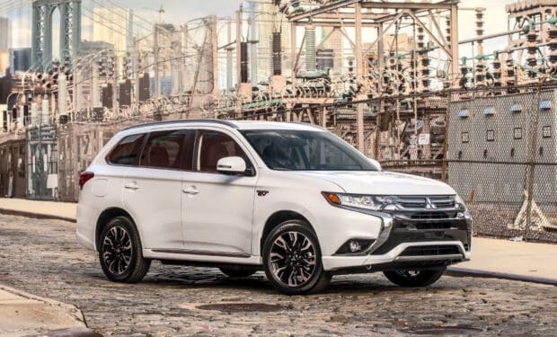 A white Mitsubishi Outlander is parked on a cobblestone street near an industrial fence, HD Desktop Wallpaper