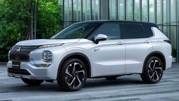 A white Mitsubishi Outlander is parked near glass windows with green plants outside, HD Desktop Wallpaper