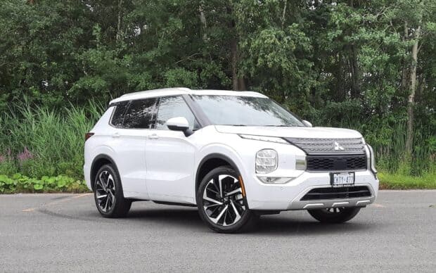 A white Mitsubishi Outlander is parked on a road with green trees in the background, HD Desktop Wallpaper