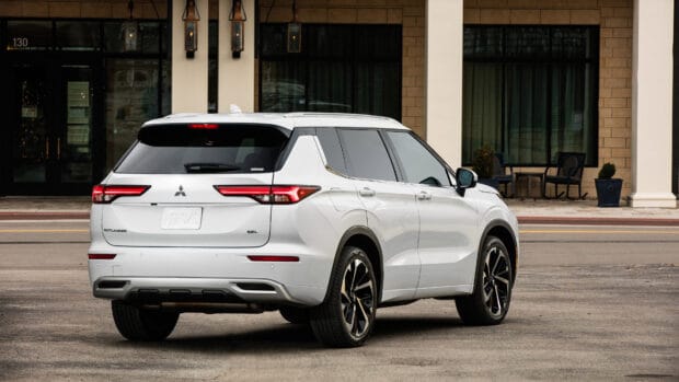 A white Mitsubishi Outlander SUV is parked on a street in front of a building, 4K Desktop Wallpaper