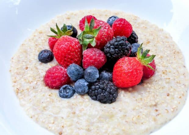A bowl of quinoa with fresh strawberries, raspberries, blueberries, and blackberries is shown, 2K Desktop Wallpaper