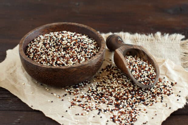 Mixed quinoa grains in a wooden bowl and scoop on paper on a wooden table, 2K Desktop Wallpaper