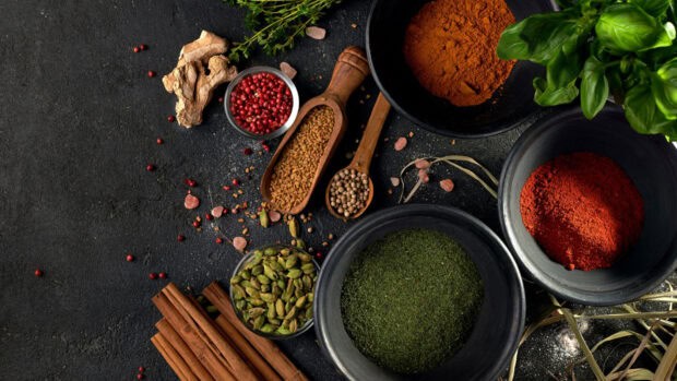 Various seasoning ingredients are arranged in bowls and spoons on a dark textured table, HD Desktop Wallpaper