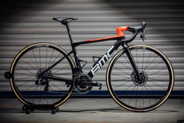 A sleek BMC bike with red and black frame standing against a metallic background, 2K Desktop Wallpaper