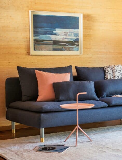 A modern living room with Ikea wallpapers features a blue sofa, cushions and a small pink side table, 2K Desktop Wallpaper