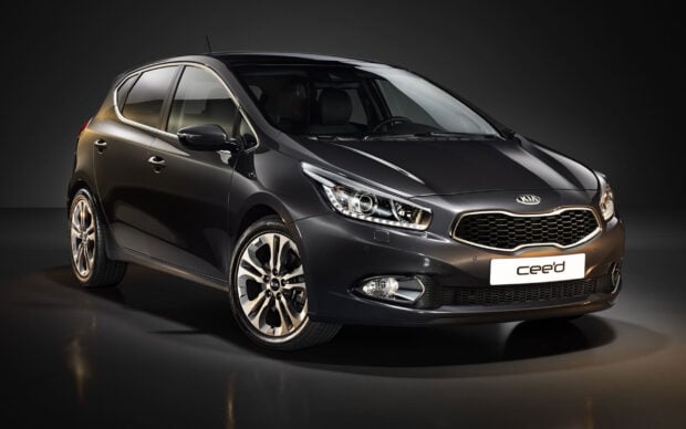 A modern Kia car is shown in dark grey with sleek lines and detailed headlights, 2K Desktop Wallpaper