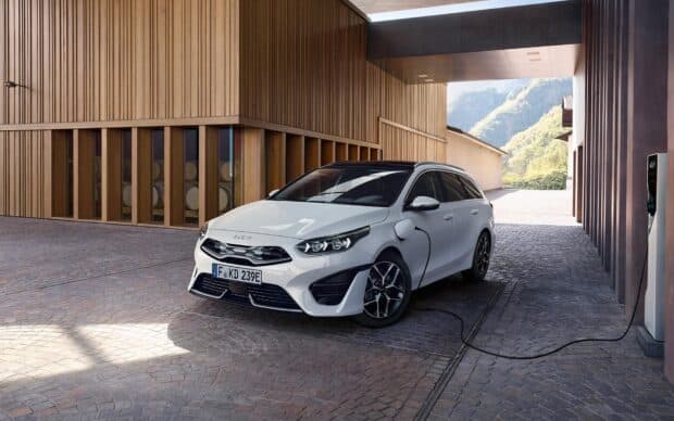 A white Kia electric car is charging at a modern station near wooden architecture, HD Desktop Wallpaper