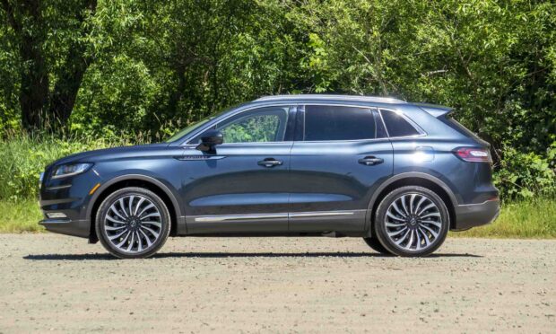 A sleek Lincoln Nautilus parked on a gravel road against a background of green trees, HD Desktop Wallpaper