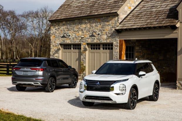 Two Mitsubishi Outlander vehicles are parked on a driveway in front of a stone garage, HD Desktop Wallpaper