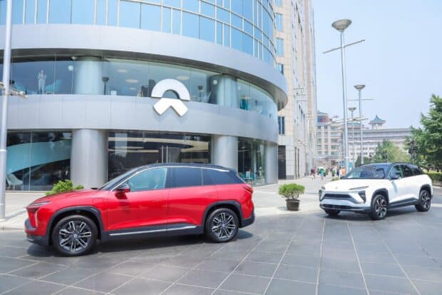 Two Nio Auto SUVs parked outside a modern glass building under clear sky, HD Desktop Wallpaper