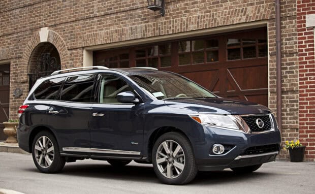 A dark blue Nissan Pathfinder parked on a street near a brick garage wall, 2K Desktop Wallpaper