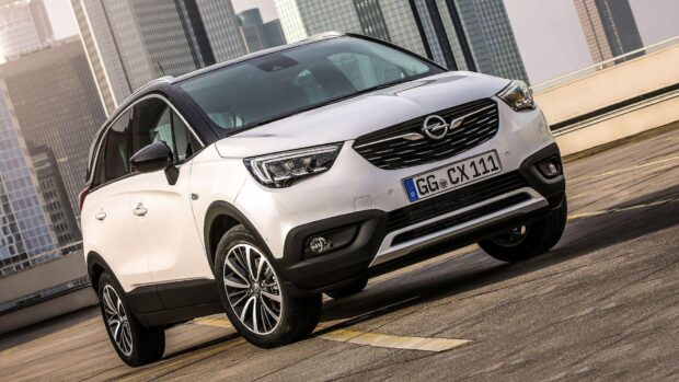 A white Opel Crossland is parked in an urban environment with high rise buildings, HD Desktop Wallpaper