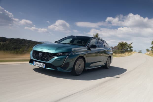 A teal Peugeot 308 car is driving fast down a rural road with clear skies and trees nearby, 2K Desktop Wallpaper