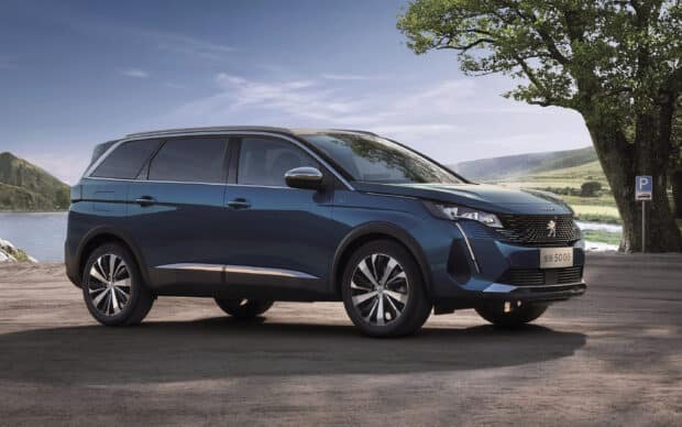A blue Peugeot 5008 is parked near a lake with hills and trees in the background, 2K Desktop Wallpaper