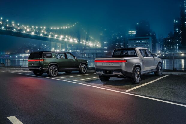 Two Rivian automotive vehicles parked near a lit bridge in the city at night, HD Desktop Wallpaper