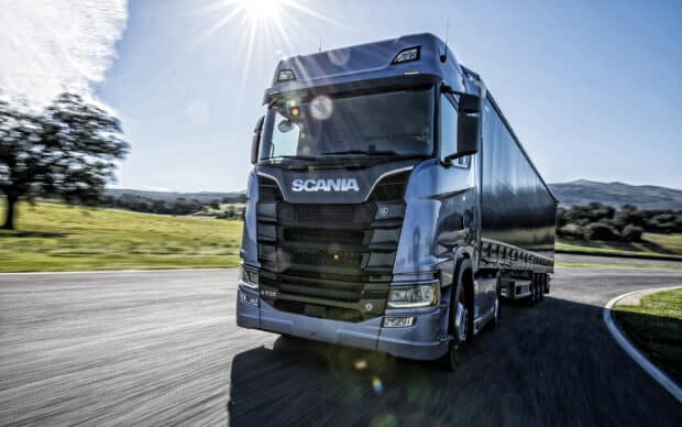 A powerful Scania truck is driving on a curved road under the sunny sky, 2K Desktop Wallpaper
