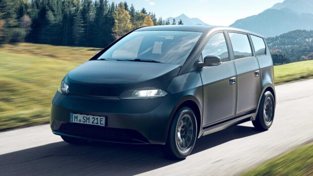 A Sono Motors vehicle is driving on a countryside road with trees and mountains in the background, HD Desktop Wallpaper