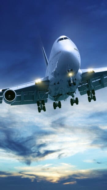 A large aircraft is flying through a partly cloudy sunset sky with its landing gear down, 2K Phone Wallpaper