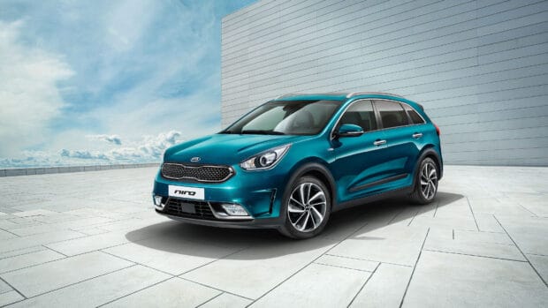 A vibrant teal Kia car is displayed outside a modern structure on a clear day, 4K Desktop Wallpaper