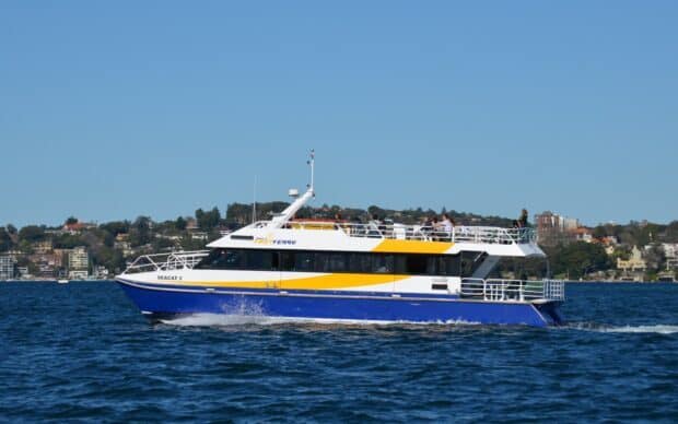 A modern ferry cruising on clear water carrying passengers near the city shore, HD Desktop Wallpaper