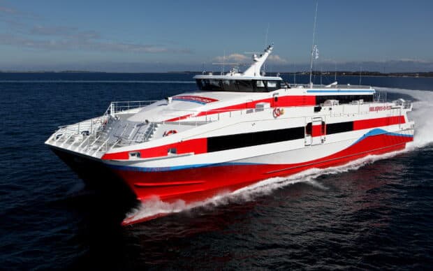 A modern ferry cruising on the calm open sea with blue skies and distant land visible, 2K Desktop Wallpaper
