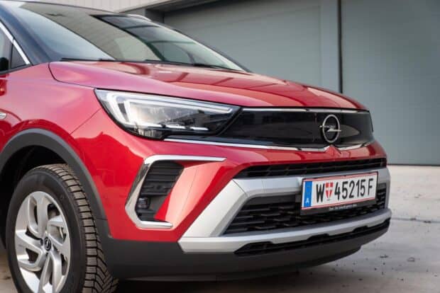 The red Opel Crossland shows its front design and headlight details in a parking area, 2K Desktop Wallpaper