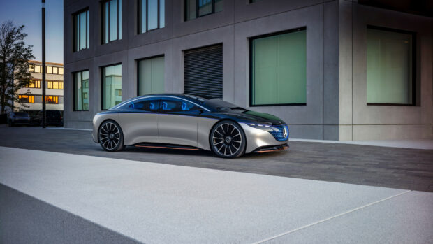 A sleek silver Mercedes Benz EQS is parked on the pavement in front of a modern office building, 2K Desktop Wallpaper