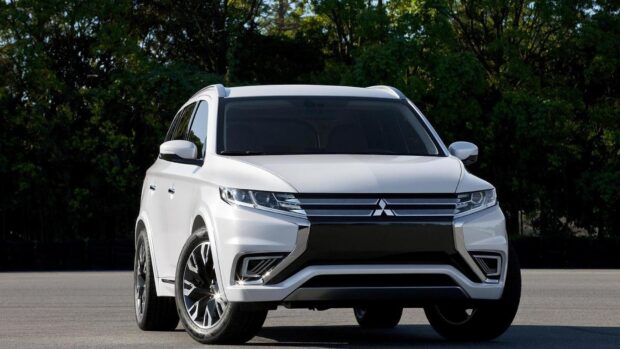 A modern white Mitsubishi Outlander SUV is parked on a road with green trees in the background, HD Desktop Wallpaper