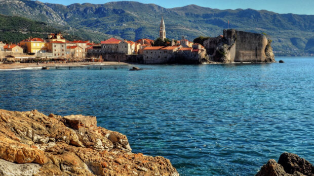 A scenic view of a coastal town in Montenegro with mountains and blue sea, 2K Desktop Wallpaper