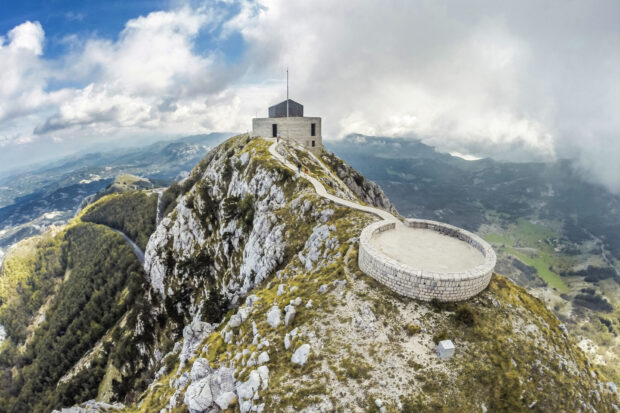 A fortress sits atop a rocky mountain surrounded by green valleys under cloudy skies in Montenegro wallpapers, HD Desktop Wallpaper