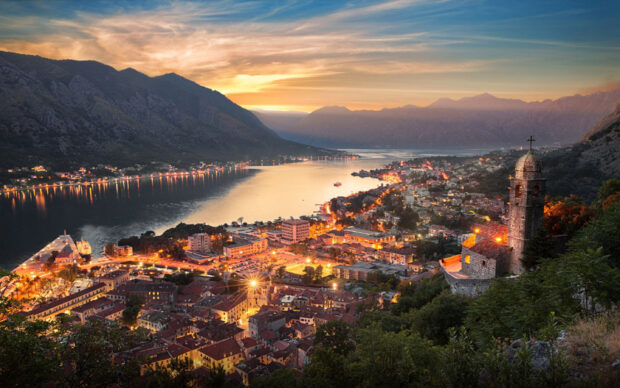 The Montenegro Wallpapers capture a stunning sunset over a coastal town with mountains in the background, 2K Desktop Wallpaper