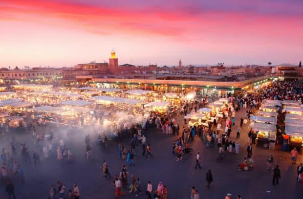 The Morocco Wallpapers show a crowded market square under a colorful sunset sky, HD Desktop Wallpaper