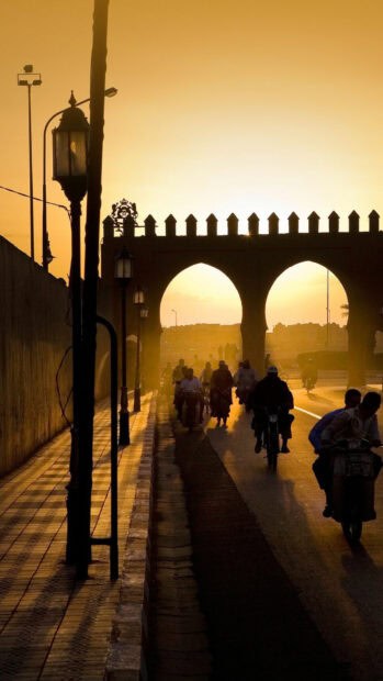 People ride motorcycles near an arch in Morocco during sunset, HD Phone Wallpaper