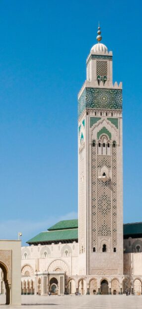A tall tower with detailed mosaic patterns stands under a clear blue sky in Morocco, HD Mobile Wallpaper